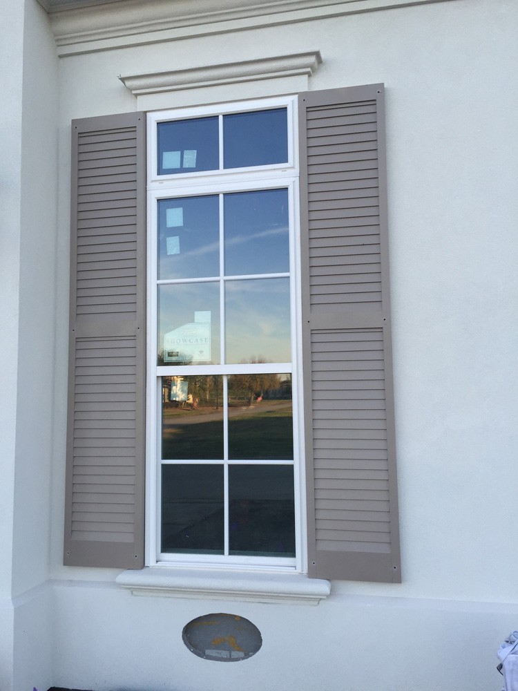 Tan shutters on white home with trimmed windows - Strong Shield