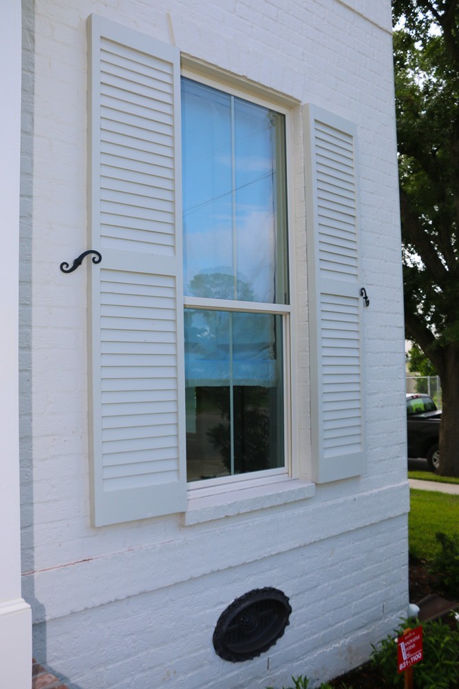 Shutters on white brick home with holdbacks - Strong Shield