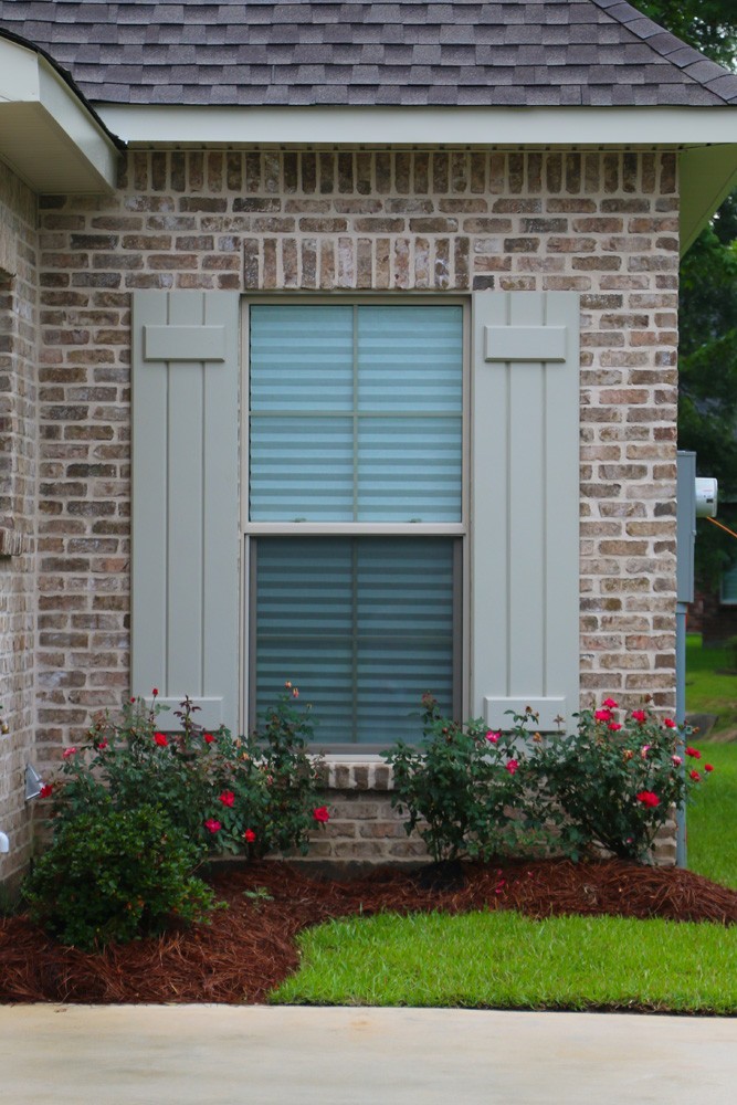 Light sage shutters on brown brick - Strong Shield