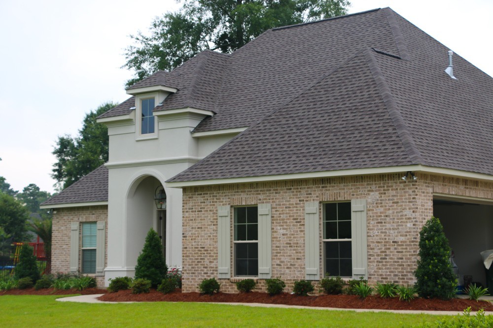 Sage shutters on tan brick and light grey stucco home - Strong Shield