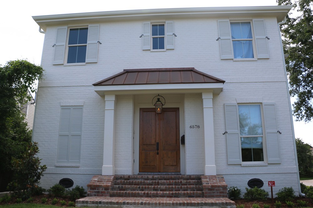 White shutters on white brick and wood door - Strong Shield