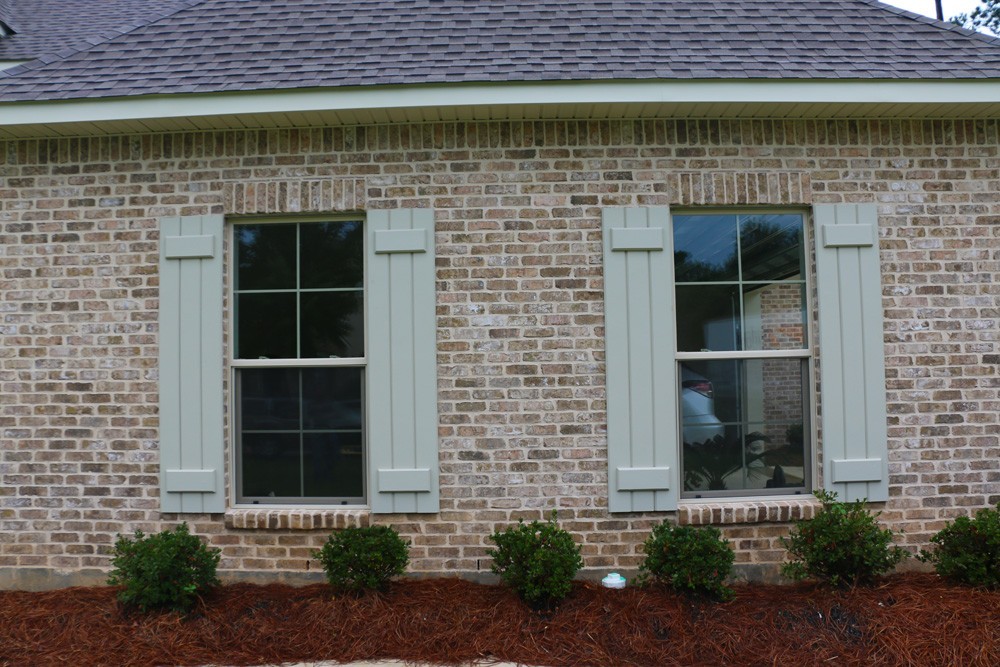 Light green shutters on brown brick - Strong Shield